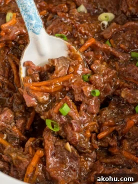 Slow Cooker Mongolian Beef Recipe — Tender Garlic Soy Beef 12 overhead of slow cooker mongolian beef with a spoon scooping some out.