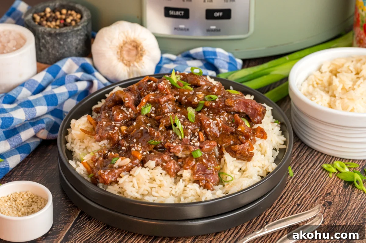 Slow Cooker Mongolian Beef Recipe — Tender Garlic Soy Beef 10 serving of slow cooker mongolian beef over rice in front of a crockpot.