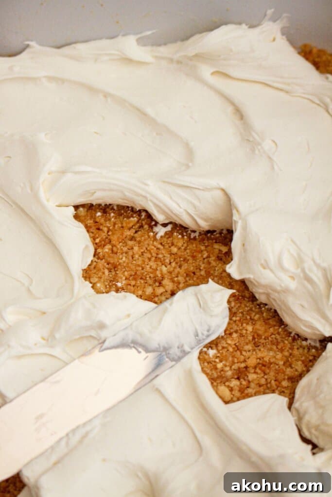 Strawberry Cheesecake Lush Dessert Recipe — No-Bake Layered Treat 6 Cream cheese layer being spread on top of crust.