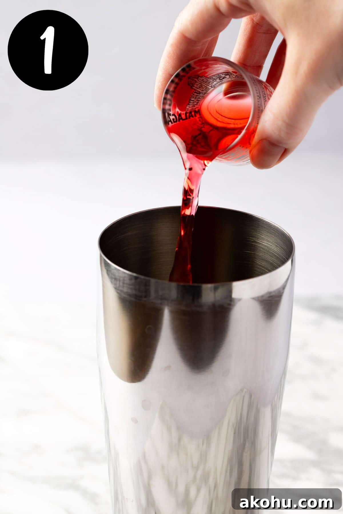 Pouring raspberry syrup into a cocktail shaker.