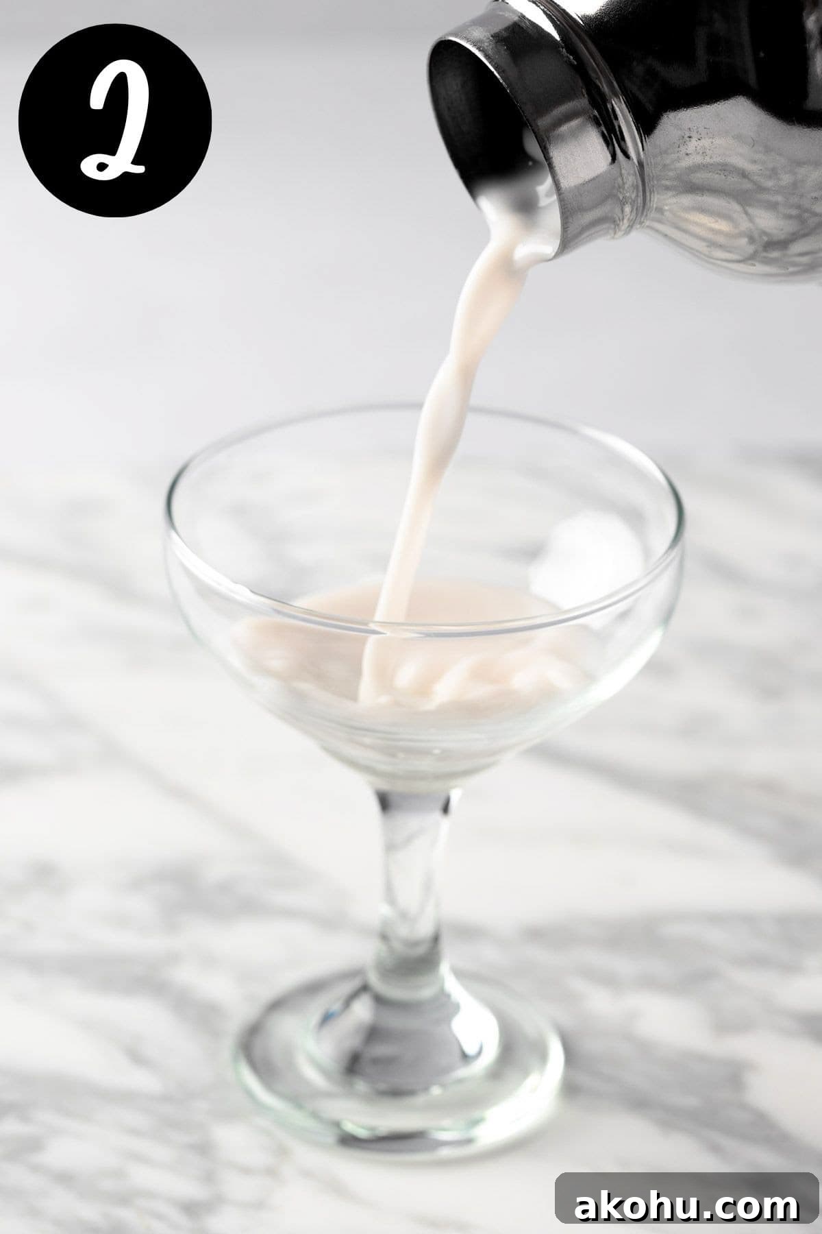 Pouring the martini from the cocktail shaker into a cocktail glass.