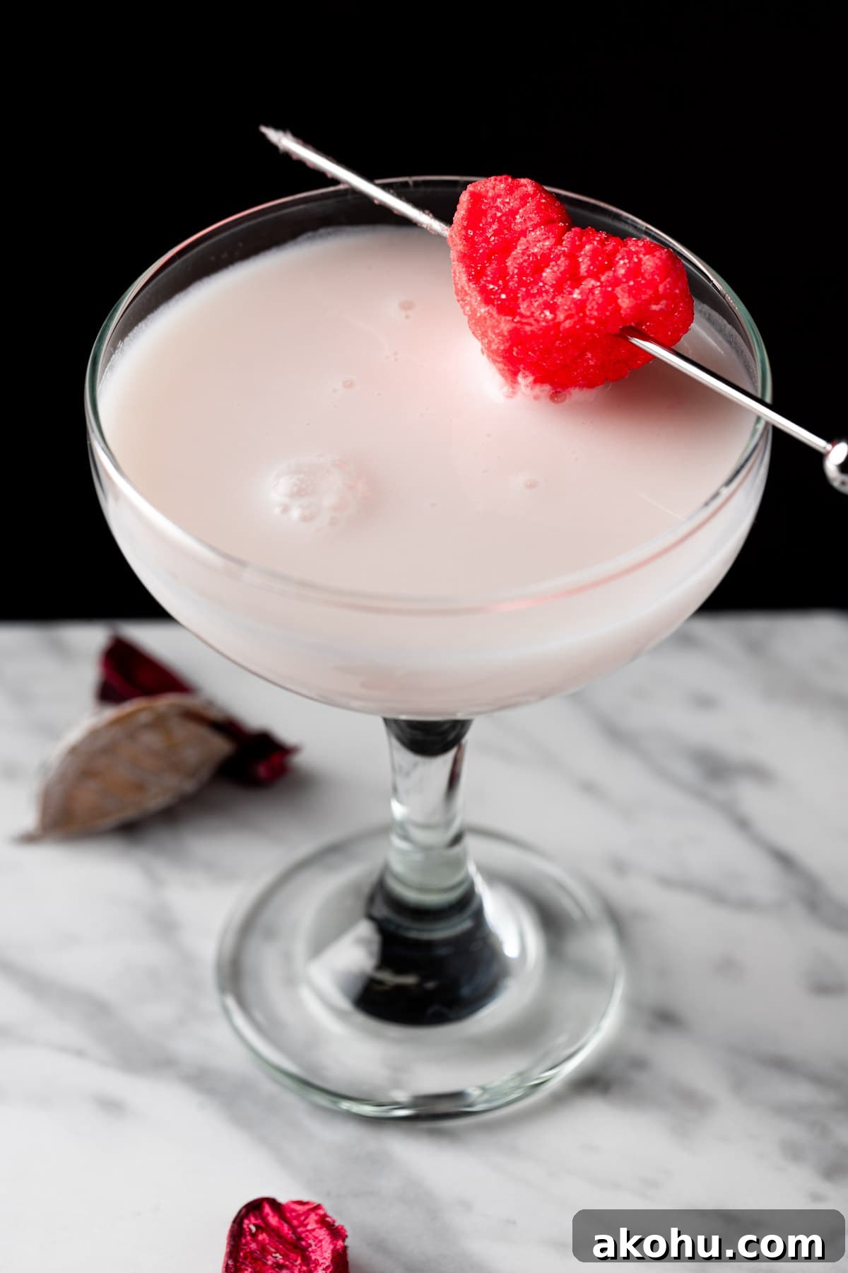 A white chocolate raspberry martini on a black background.