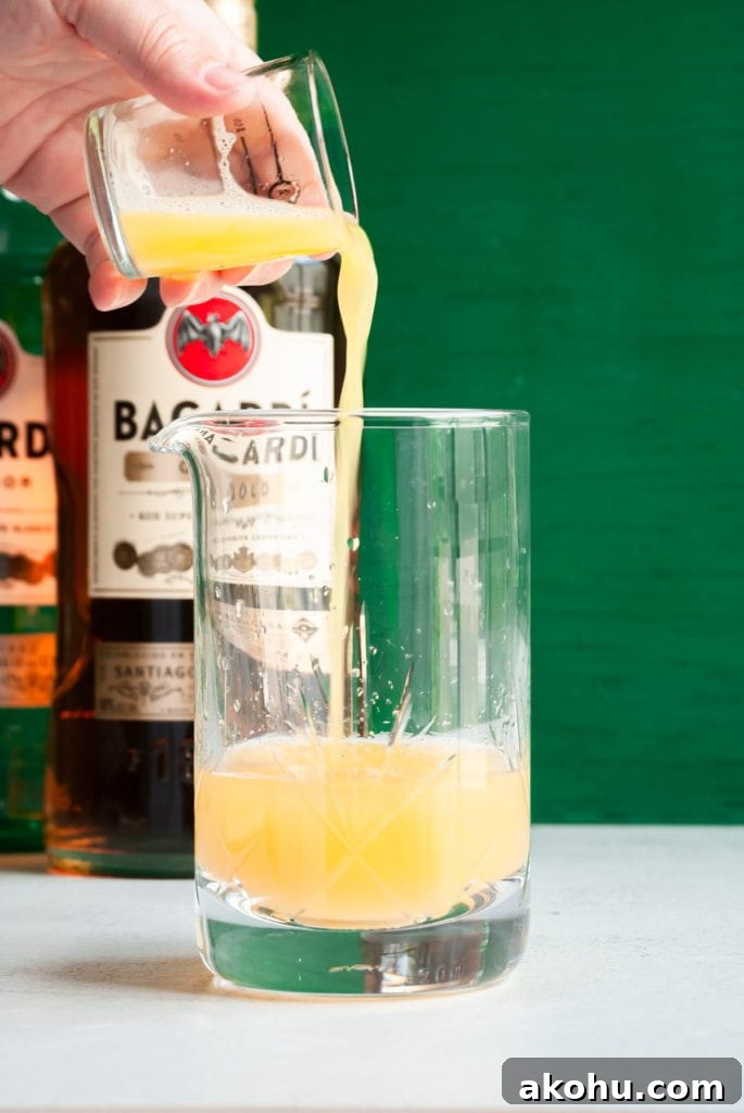 Refreshing Bacardi Rum Punch Recipe for Parties 4 Pouring juice into cocktail mixing glass.