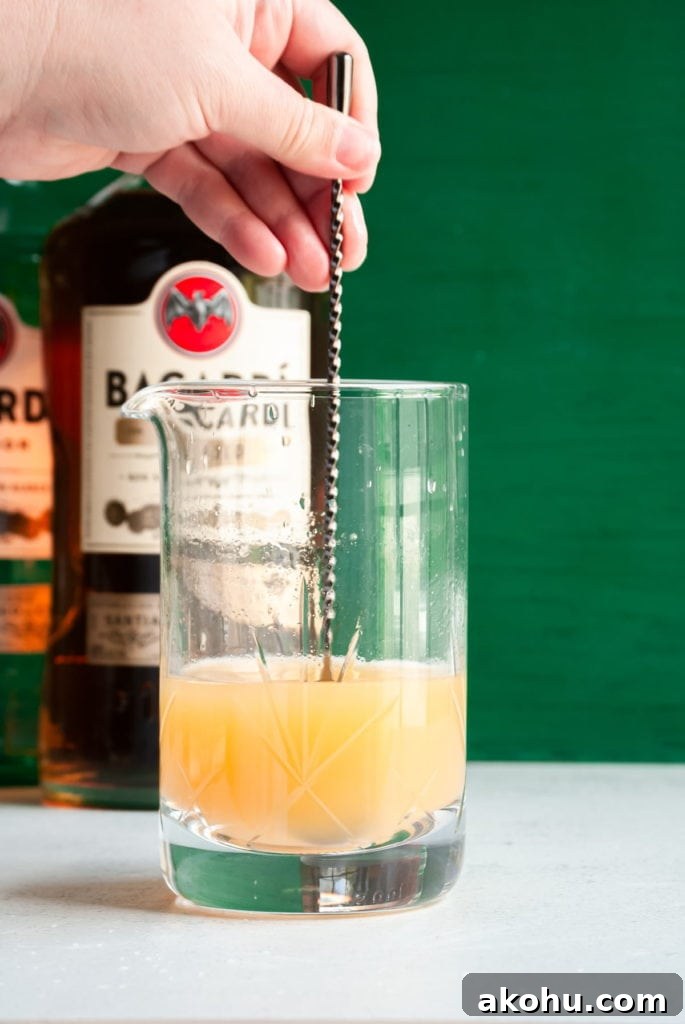 Refreshing Bacardi Rum Punch Recipe for Parties 5 Mixing cocktail with long spoon.