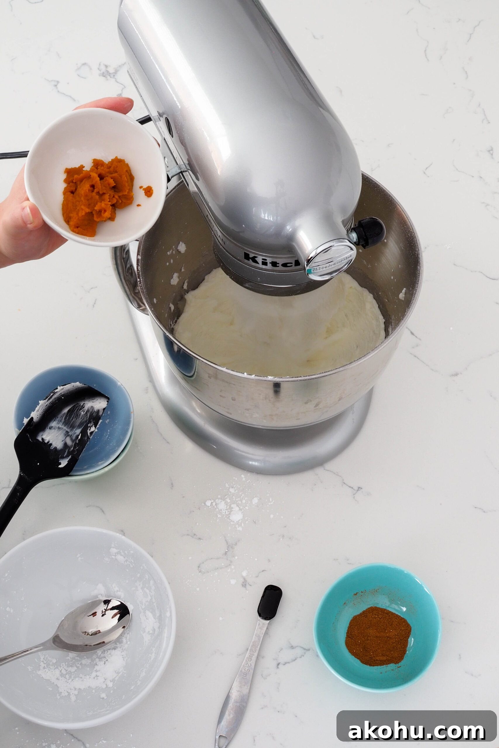 Pumpkin puree is about to be added to a stand mixer with cream cheese buttercream.