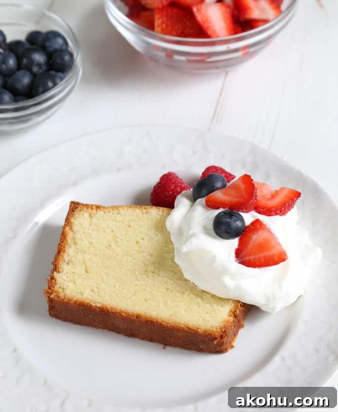 A close up of pound cake with whip cream and fruit on white plate 