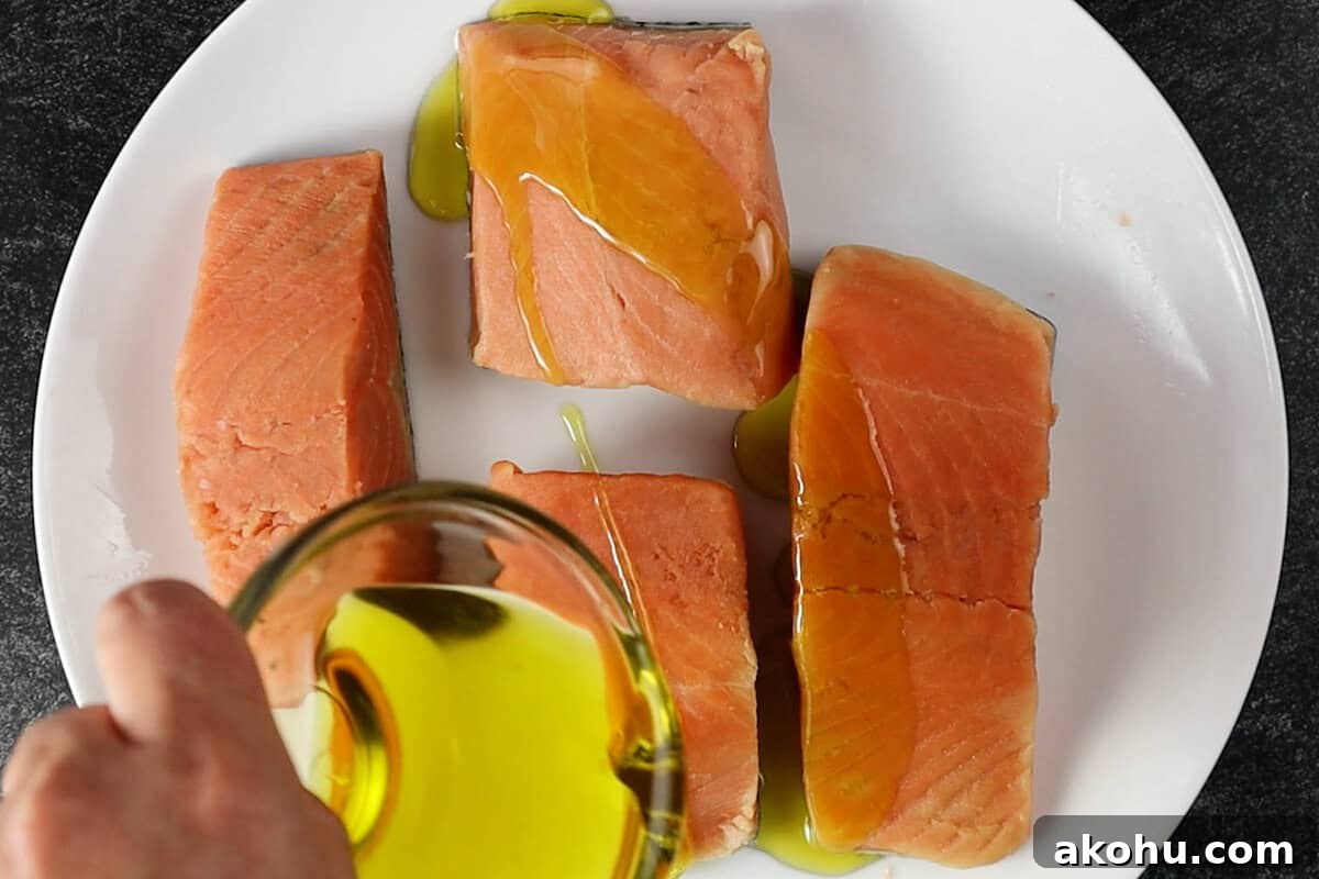Pan-Seared Salmon with Fresh Mango Salsa 7 coating salmon in olive oil on white plate.