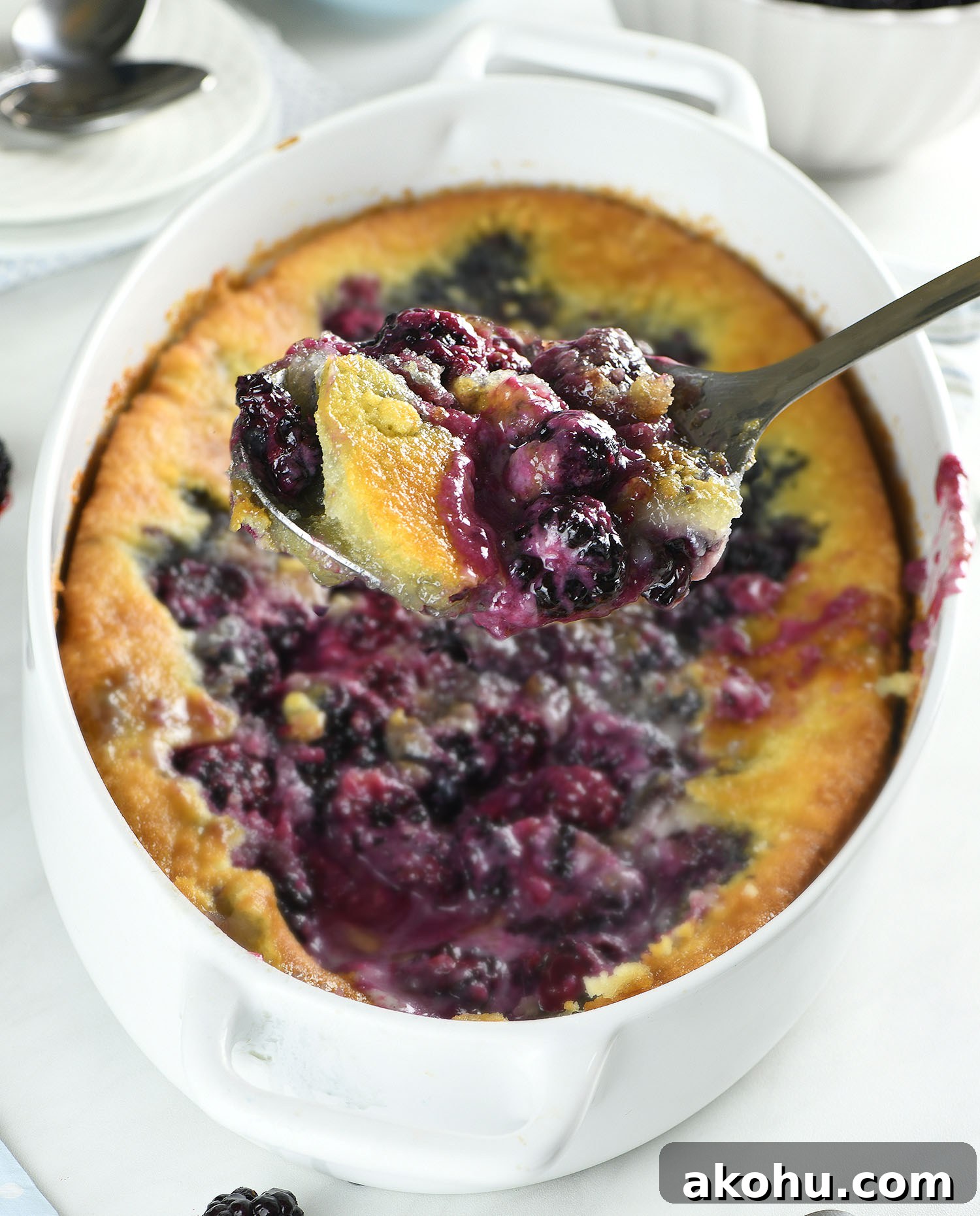Easy blackberry cobbler being scooped from a baking dish with juicy blackberries and golden buttery topping.