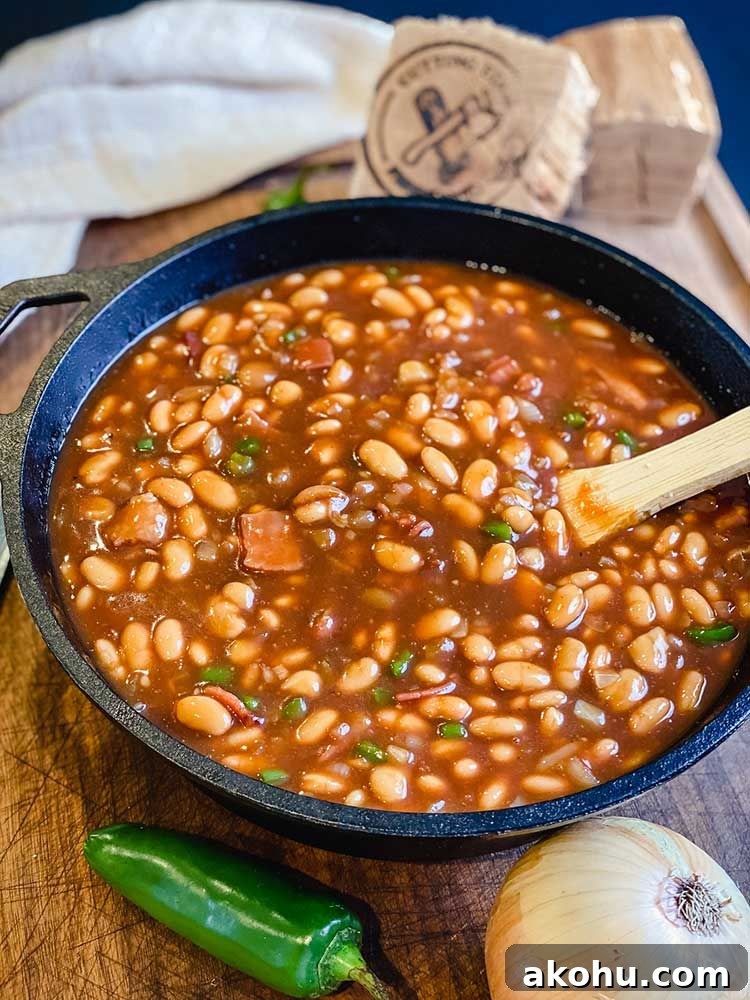 smoked baked beans resting with hickory chunk and wooden spoon