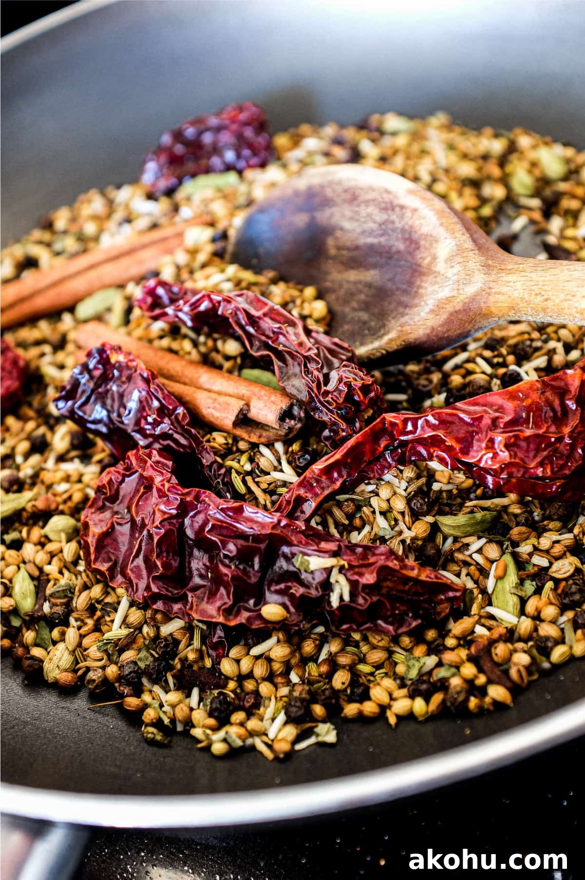 Sri Lankan Curry Powder Recipe | cookeatworld.com Whole spices dry frying in a pan with a wooden spoon