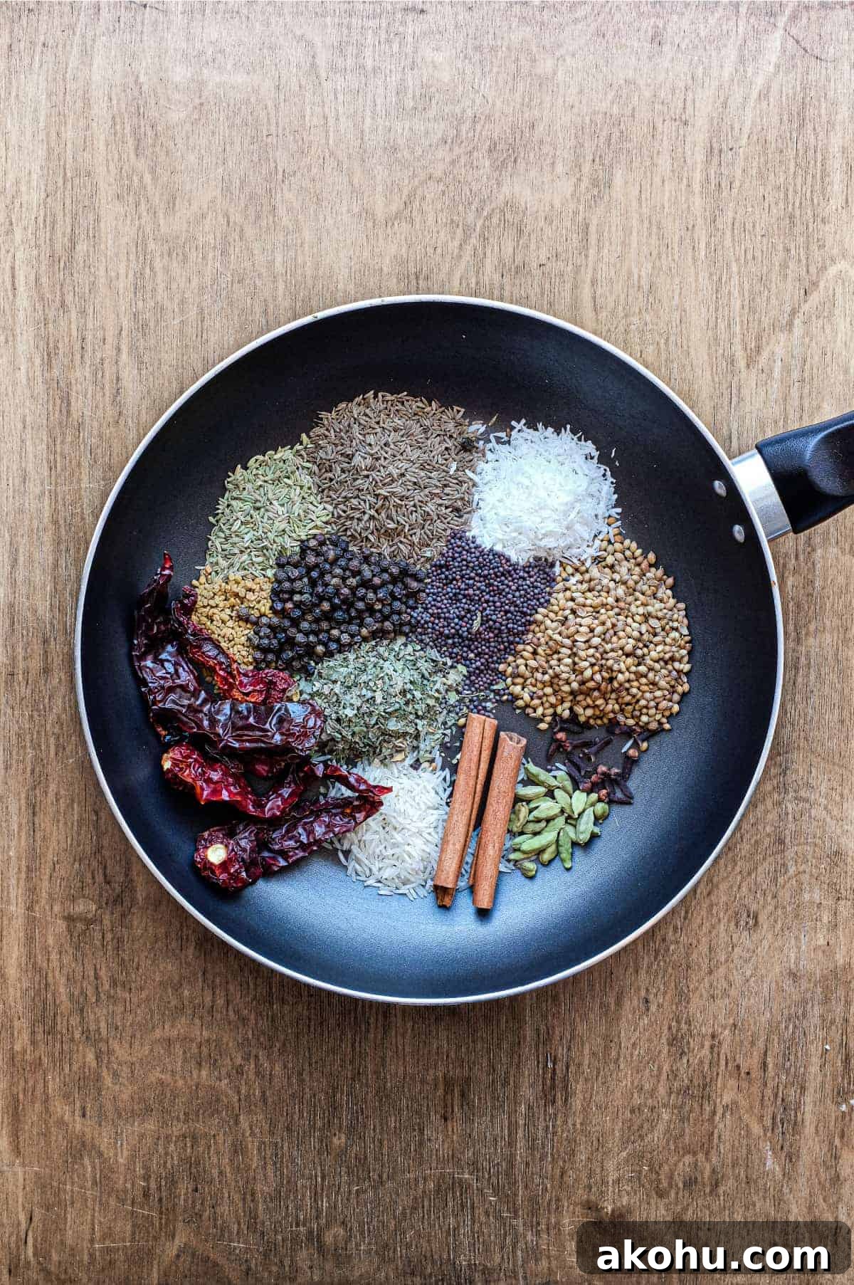 Sri Lankan Curry Powder Recipe | cookeatworld.com A pan with whole spices including coriander seeds, fennel, cinnamon, rice, chillies, cumin, fenugreek, coconut and more