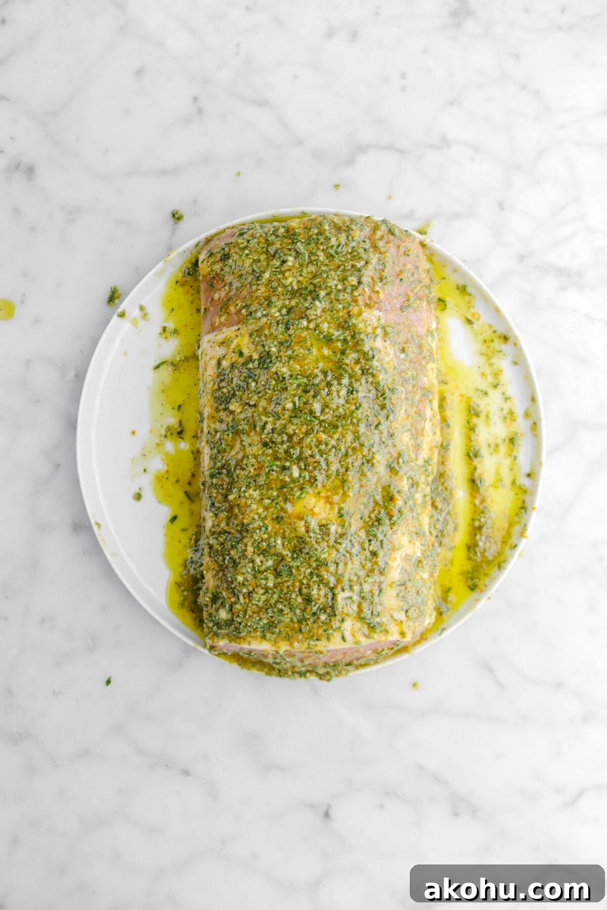 pork loin covered in marinade on white plate.