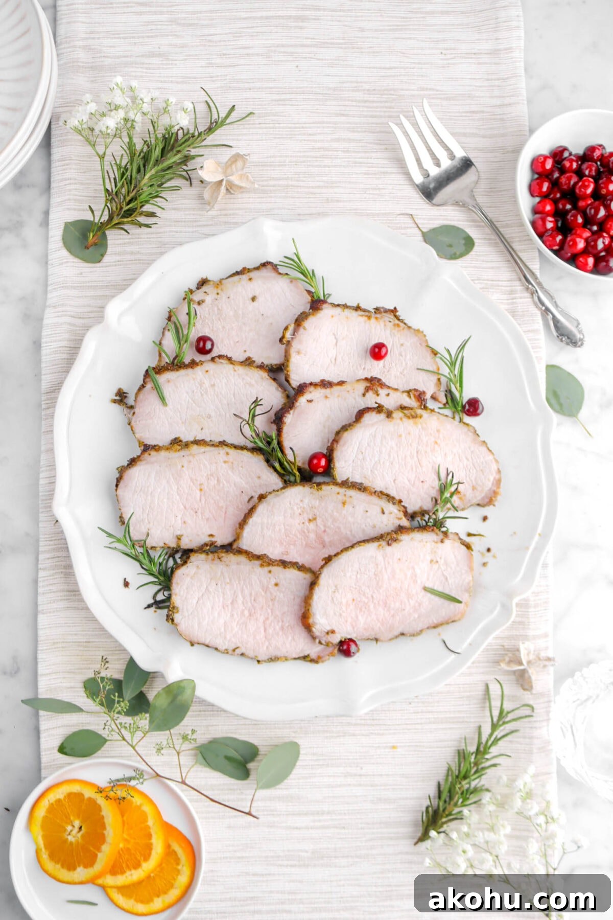 nine slices of pork on round platter with rosemary sprigs and cranberries.