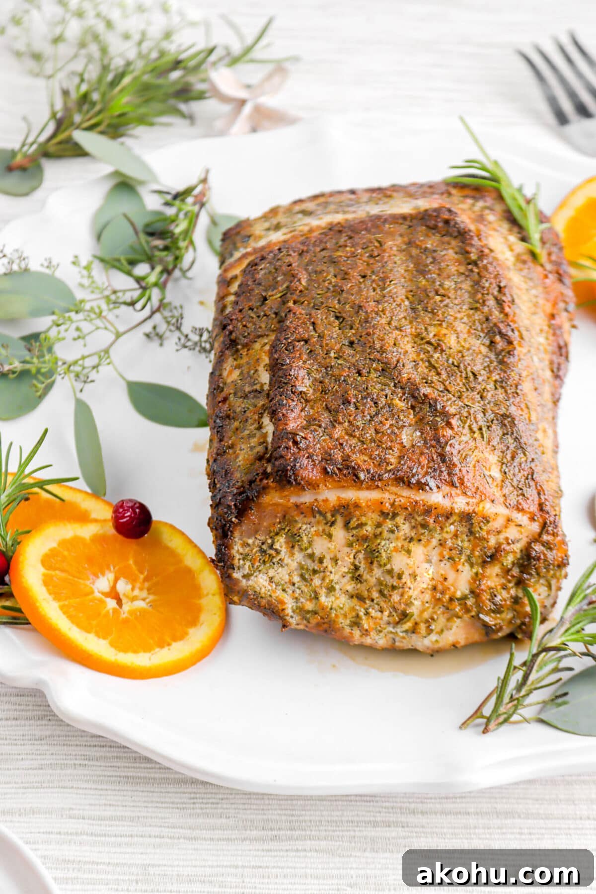 angled close up of roasted pork tenderloin on white platter.