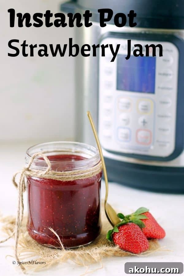 Holiday Instant Pot Strawberry Jam Recipe 2 A small jam full of strawberry jam made in the instant pot with two fresh strawberries on the side and instant pot in the background