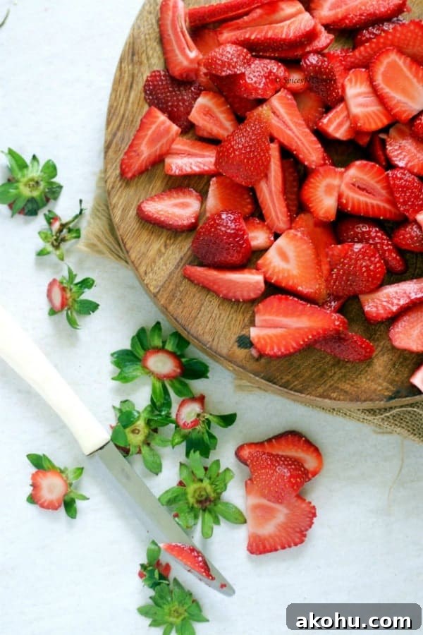 Holiday Instant Pot Strawberry Jam Recipe 5 chopped strawberries placed in the wooden board with a butter knife and some scattered strawberry leaves