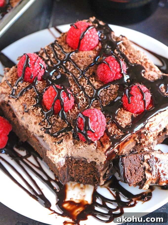 Chocolate Baileys Poke Cake Recipe 16 A slice of Chocolate Baileys poke cake with chocolate sauce and raspberries
