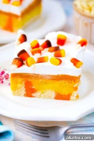 candy corn poke cake with a pumpkin spice pudding layer, whipped cream and candy corn