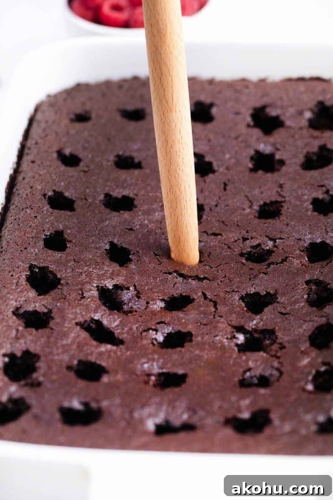 Chocolate Baileys Poke Cake Recipe 9 poking holes with a wooden spoon in a chocolate cake