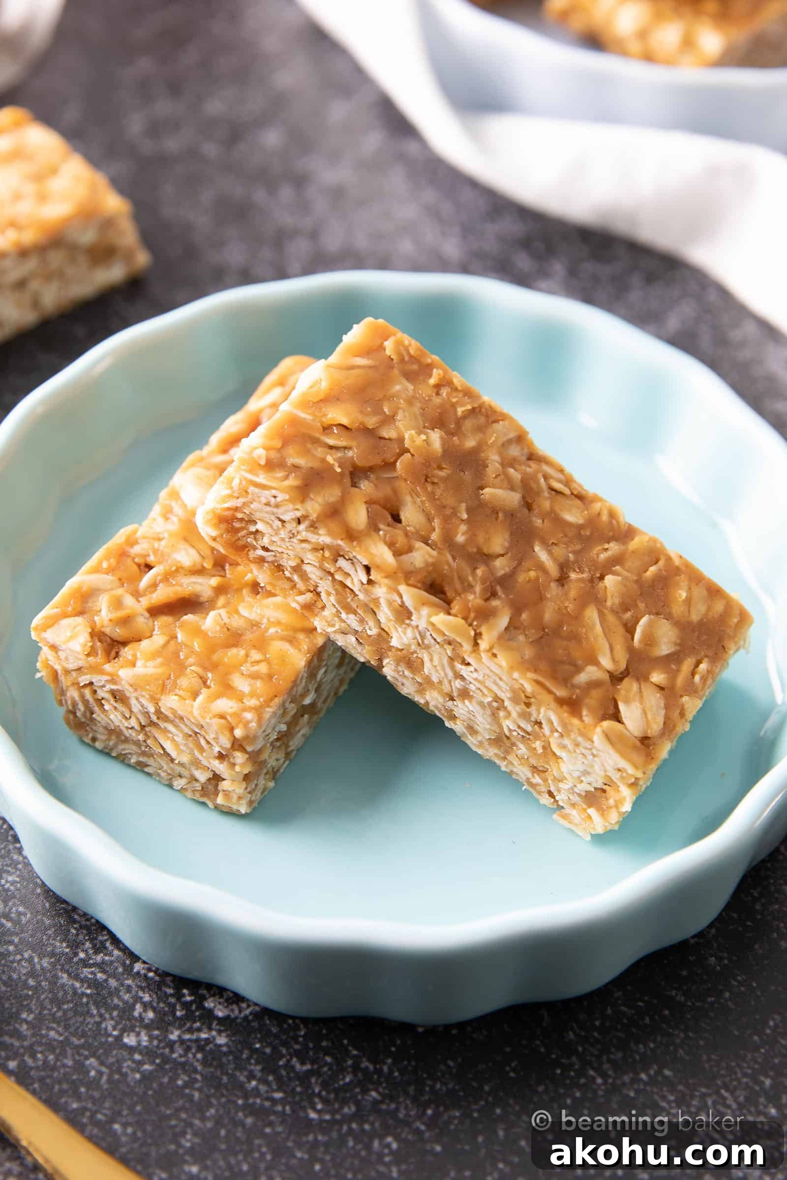 3-Ingredient Peanut Butter Granola Bars 2 Two granola bars stacked on top of each other in a blue dish, sitting on a dark gray table.