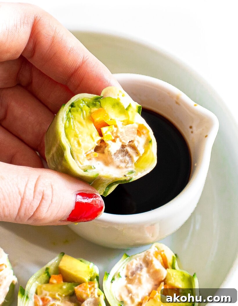 Hand holding a piece of cucumber tuna sushi and dipping it in soy sauce.
