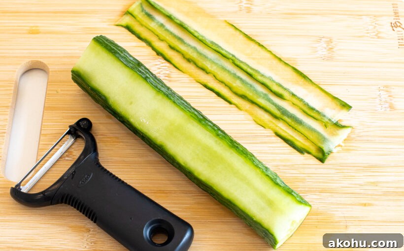 Cucumber being sliced into thin pieces with a potato peeler.