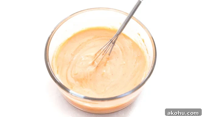 Spicy mayo in a glass bowl with a whisk.
