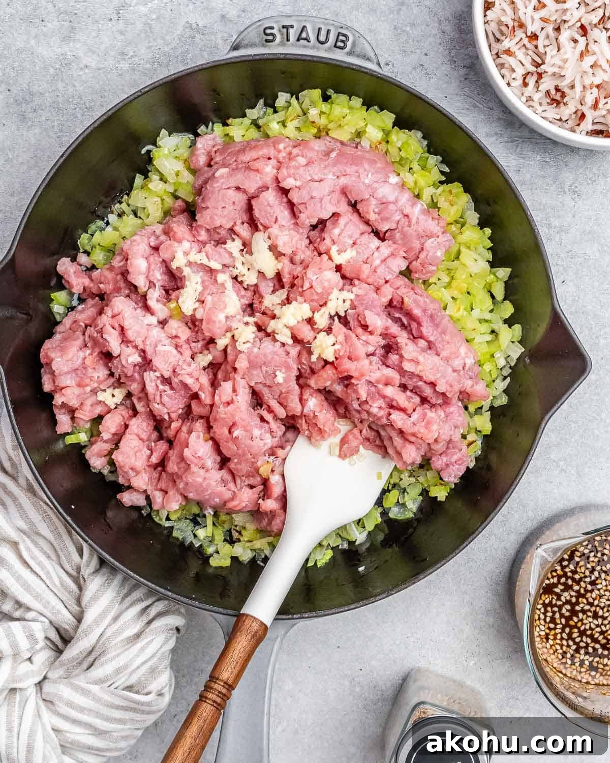 Stirring raw ground turkey with a white spatula in a skillet.