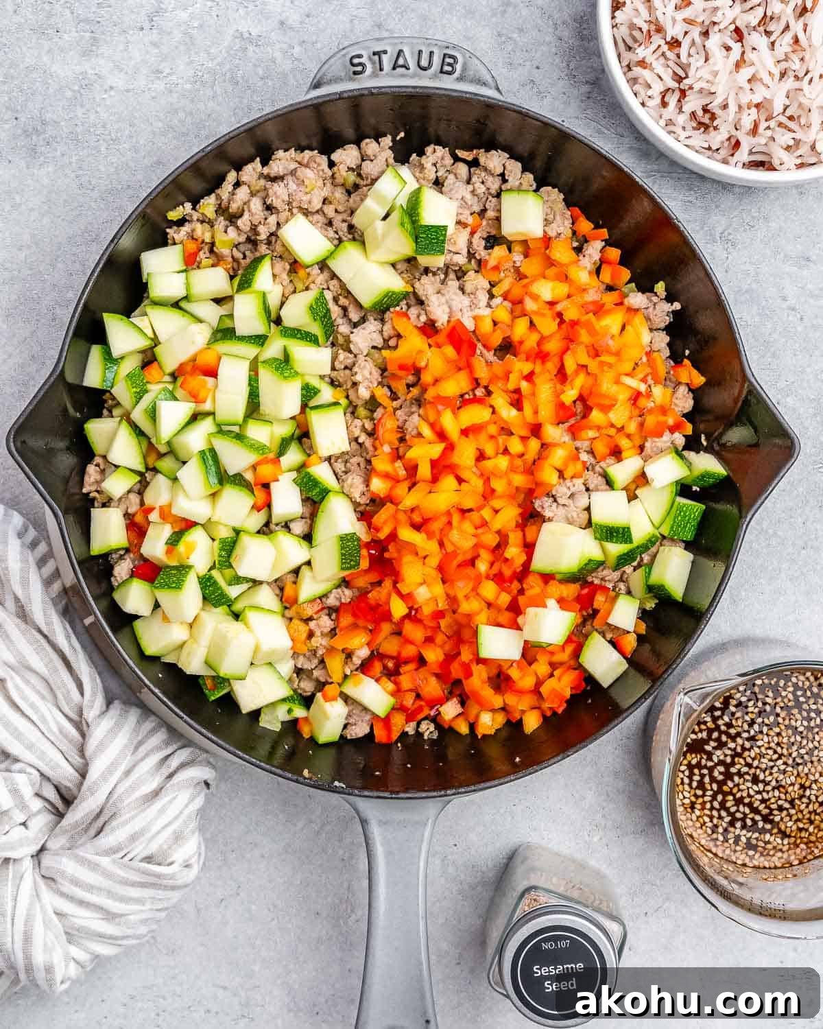 Brightly colored vegetables on top of ground turkey in a skillet.