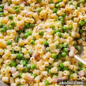 Close up shot of piselli pasta with peas and bacon bits in a large pan